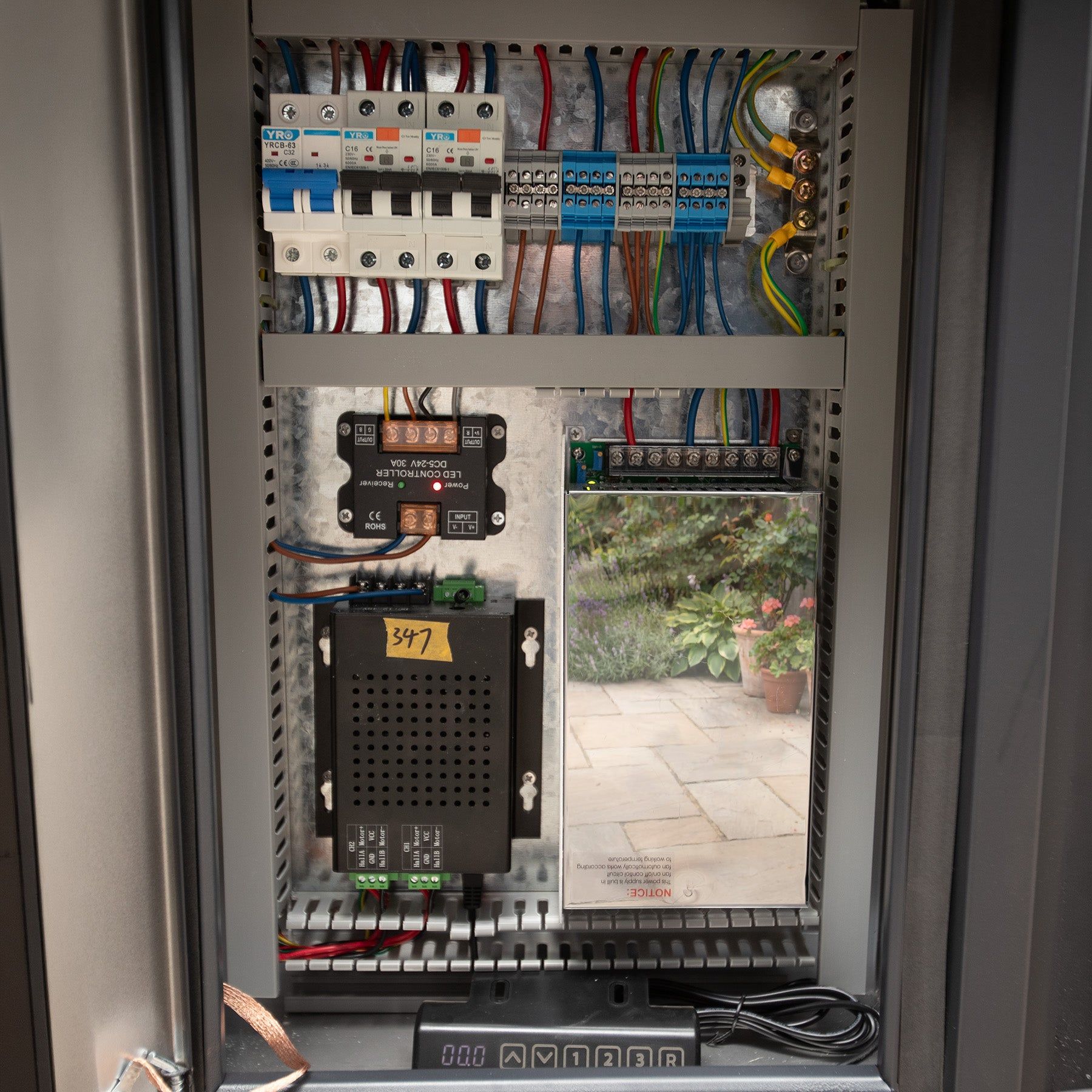 The consumer unit behind a cube's service panel, breakers, terminals and the lighting controller wired and labelled (supplier photograph)