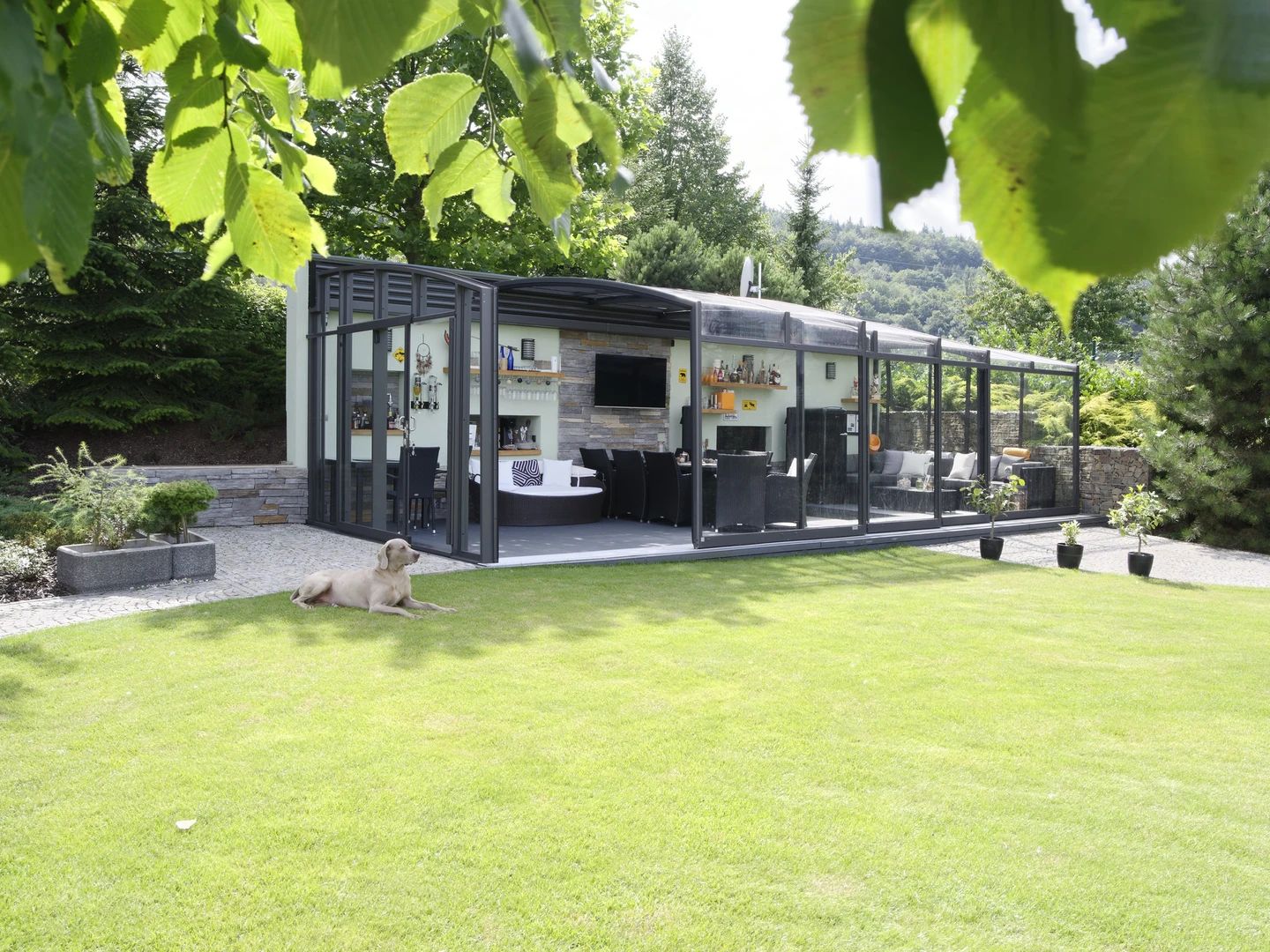 A glass garden room with its sliding walls opened onto a lawn