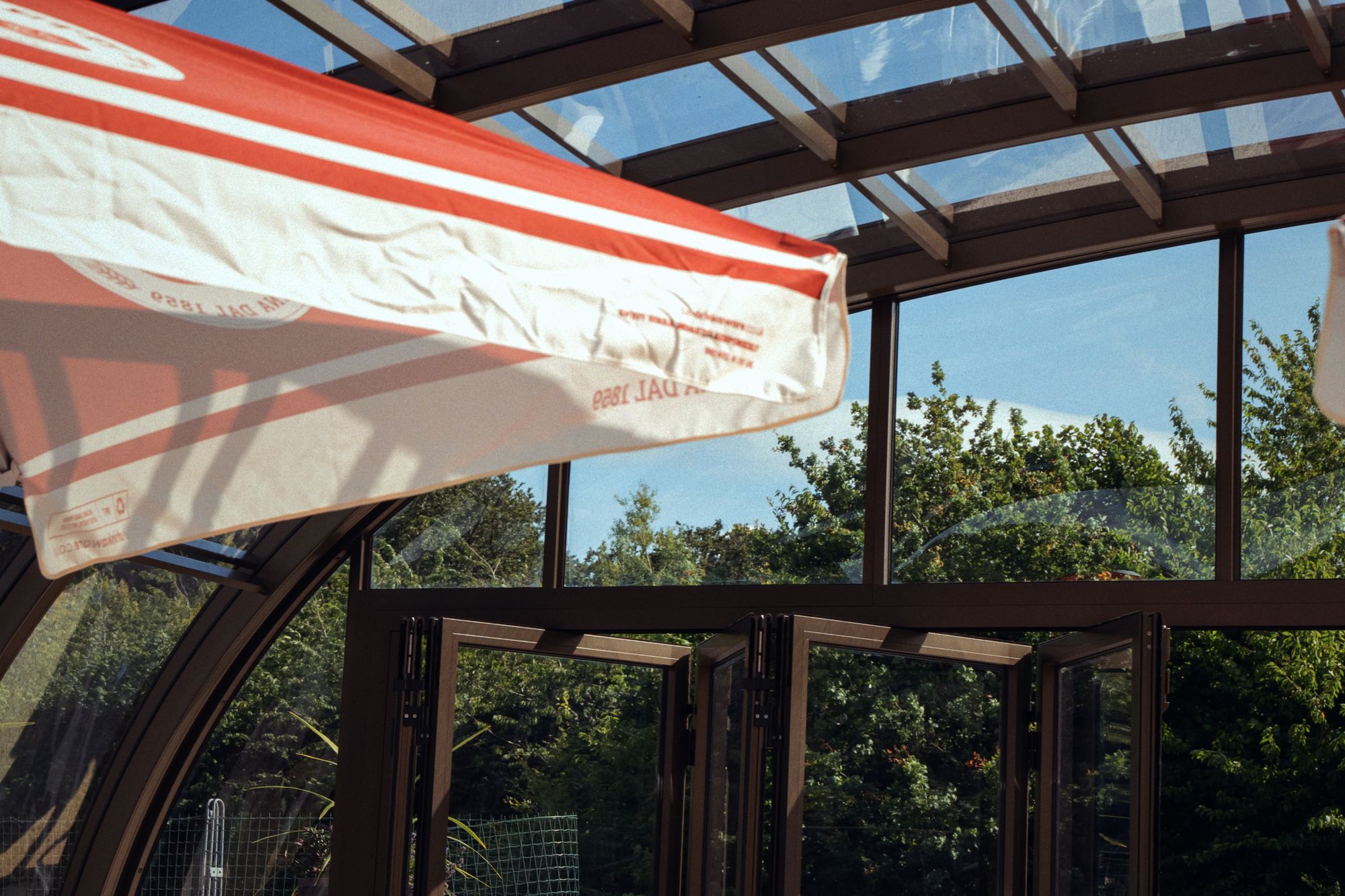 Looking up inside the glasshouse at the arched frame and the folding doors at the end